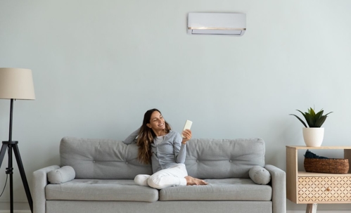 woman on the couch adjusting AC unit