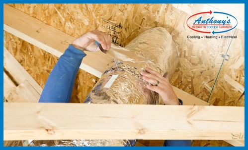 HVAC worker repairing air duct in attic