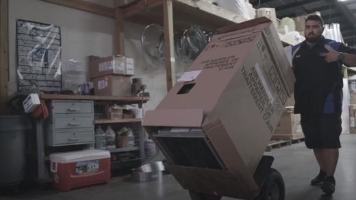 Tech pushing HVAC system on a dolly.
